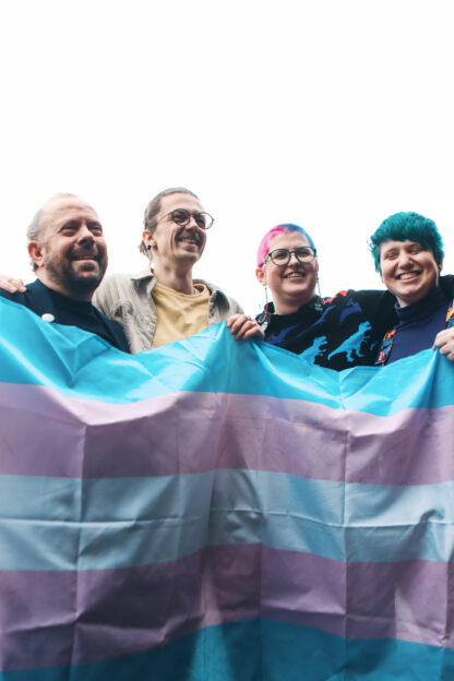 Vier mensen houden samen de transgender vlag voor zich.